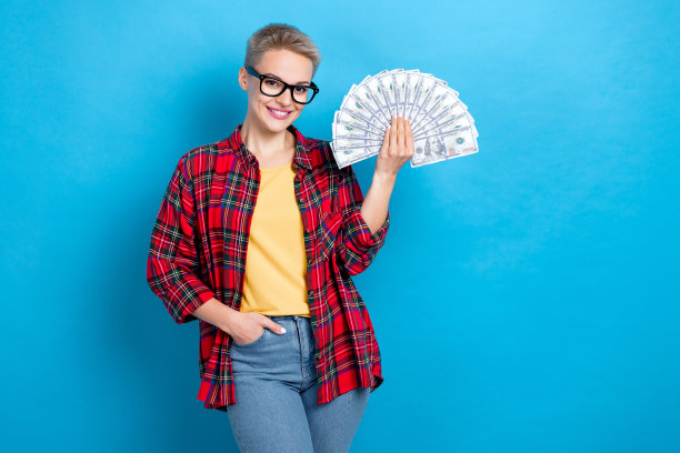 照片华丽的漂亮积极的女孩与短发型穿着红衬衫的手在口袋里拿钱孤立的蓝色背景图片下载