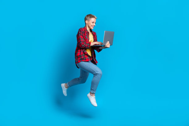 年轻活跃的学生大学女自由职业者远程教育课程持有笔记本电脑孤立的蓝色背景的全长照片图片下载