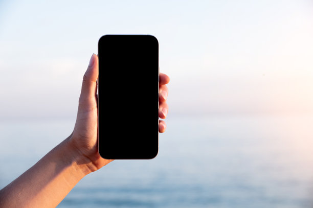 一个白种女人在海边打电话，背景是日落。空白智能手机屏幕模型，旅游，保险应用图片下载
