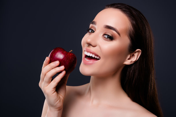 照片中快乐的女孩用健康的牙齿吃苹果孤立的深色背景图片下载