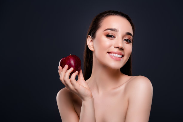 照片迷人的女孩女士牙齿微笑拿着新鲜的苹果孤立的深色背景图片下载
