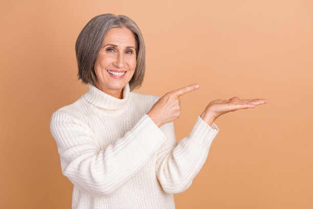 照片正面迷人开朗的促销员商务女士白色毛衣手掌直接手指模拟对象隔离在米色背景图片下载