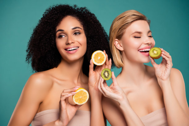 照片中的两人女孩品尝柠檬猕猴桃孤立的青色背景图片下载