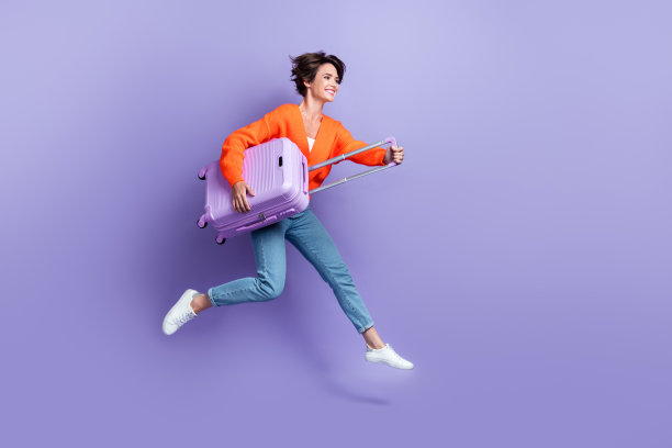 粗心活跃的旅游女孩的全身照片跳跃奔跑的行李看起来空的空间机场广告孤立的紫色背景图片下载