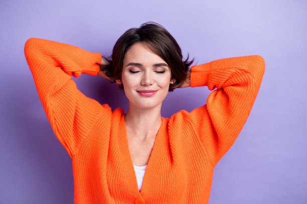 照片正面漂亮的女士穿着时髦的衣服，手臂在头后享受放松休息孤立的紫色背景图片下载