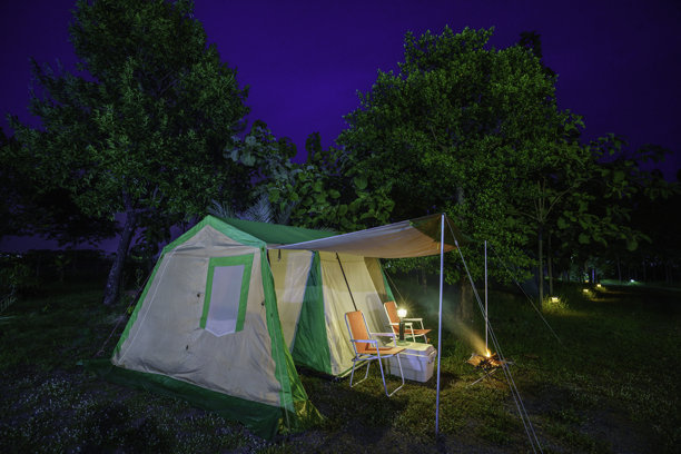 夜晚的露营帐篷，复古的小屋帐篷，古董灯笼，复古的椅子，以及森林里木制桌子上的户外咖啡制作设备图片下载