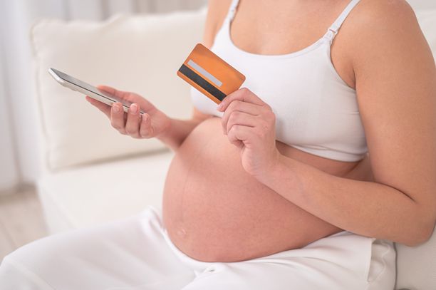 一名孕妇手持智能手机和信用卡。网上购物的概念。图片下载