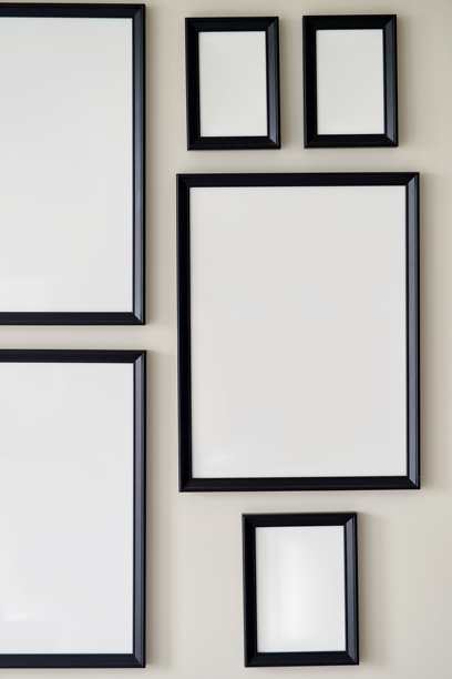 灰色的墙上挂着大小不一的相框照片。模型。图片下载