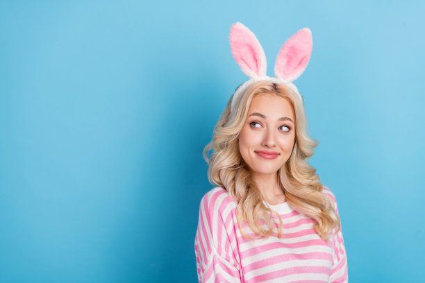 照片的滑稽梦幻的女士穿着粉红色的套头衫兔子耳朵头带回头看空空间孤立的蓝色背景图片下载