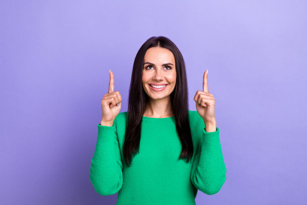 肖像照片迷人的微笑积极年轻的西班牙女士穿着绿色时髦的套头衫，手指点在紫罗兰色背景上看起来很孤立图片下载