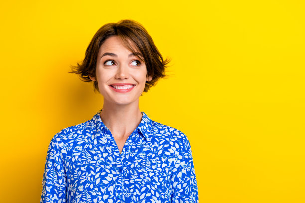 照片中可爱有趣的年轻女士穿着印花衬衫，看起来空空荡荡，孤立的黄色背景图片下载