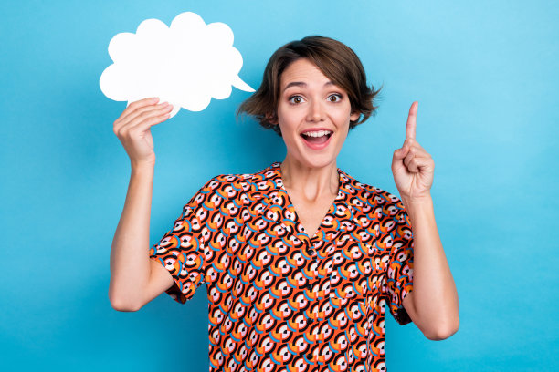 照片上时髦的女人穿着印花衬衫，用手指指着云，空白的空间孤立的蓝色背景图片下载