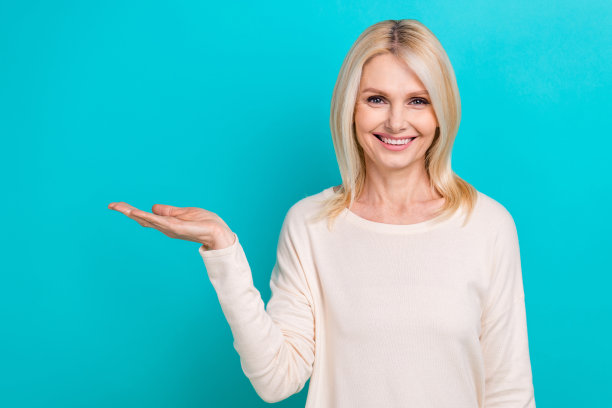 照片正面迷人的女子穿着白色衬衫，抱着手臂，空旷的空间孤立的绿松石色背景图片下载