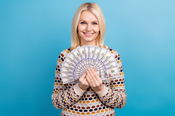 照片积极开朗的女士穿着时髦的衣服，有很多钱储蓄赢得彩票孤立的蓝色背景图片下载