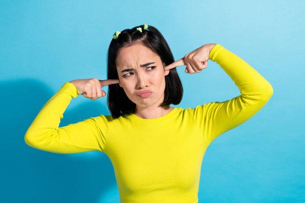 不高兴的有趣的年轻韩国女孩的照片激怒了坏的反应暴躁的手指闭上耳朵不喜欢听人孤立的蓝色背景图片下载