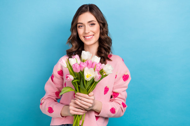 照片肖像迷人的女人拿着郁金香花束穿着时尚的粉红色草莓印花服装孤立的蓝色背景图片下载