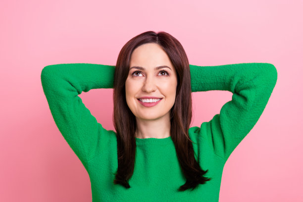 照片中开朗积极的女性戴着绿色的手臂，抬头仰望空旷的空间，孤立的粉红色背景图片下载