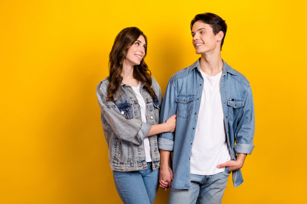 照片中，甜蜜迷人的情侣穿着牛仔布散步聊天，空白空间孤立的黄色背景图片下载