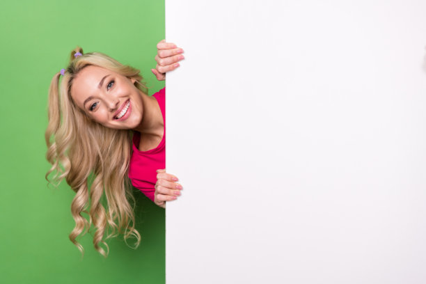 照片的华丽时髦的女士露齿微笑窥视背后的空白空间标语牌孤立的绿色背景图片下载
