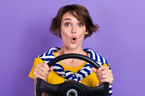 照片的惊讶印象的女士穿着时尚的衣服，抱着车轮印象高速快速的新车孤立的紫色背景图片下载