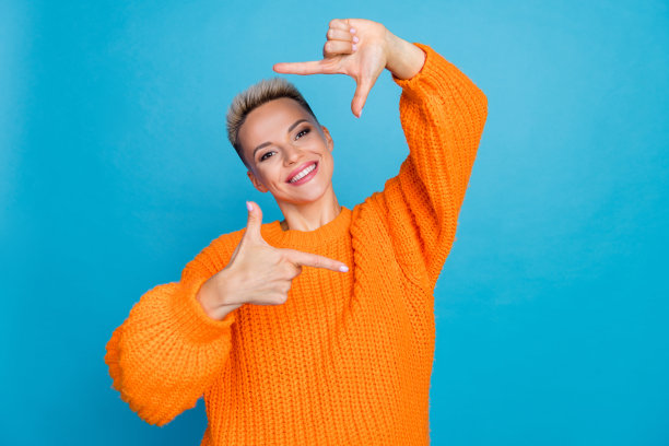 照片的漂亮可爱的女人穿着针织套头衫，显示手臂照片拍摄孤立的蓝色背景图片下载