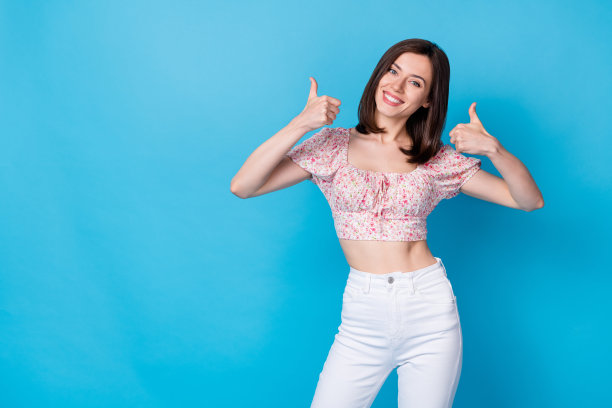 年轻迷人的漂亮可爱的女人的肖像照片女孩拇指向上微笑推荐空白空间孤立的蓝色背景图片下载