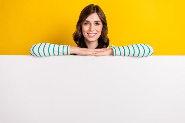 照片好心情可爱的女孩波浪发型穿着条纹衬衫手牵着手在白色墙壁孤立的黄色背景图片下载