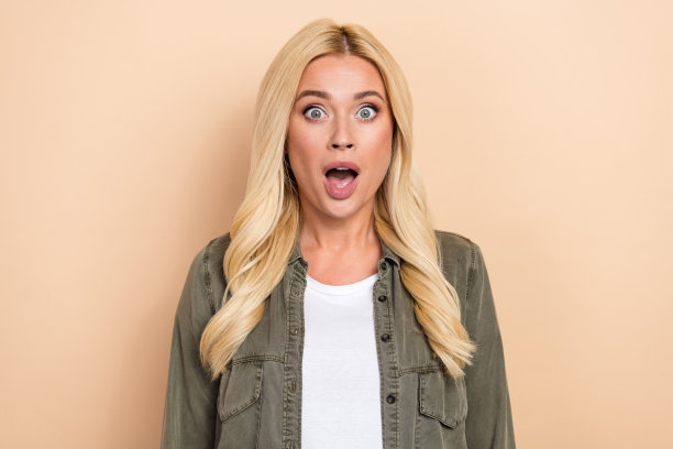 照片上光鲜亮丽的女子穿着卡其布衬衫微笑着张开嘴孤立的米色背景图片下载