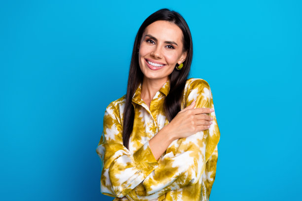 魅力的照片可爱的漂亮的女人穿着时尚的衣服拥抱自己孤立的蓝色背景图片下载