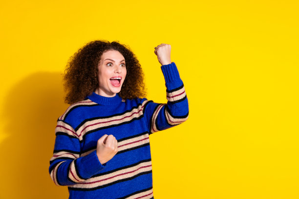 照片中，穿着毛衣、烫发的女人欣喜若狂，凝视着黑色星期五，黄色背景上的空白空间图片下载