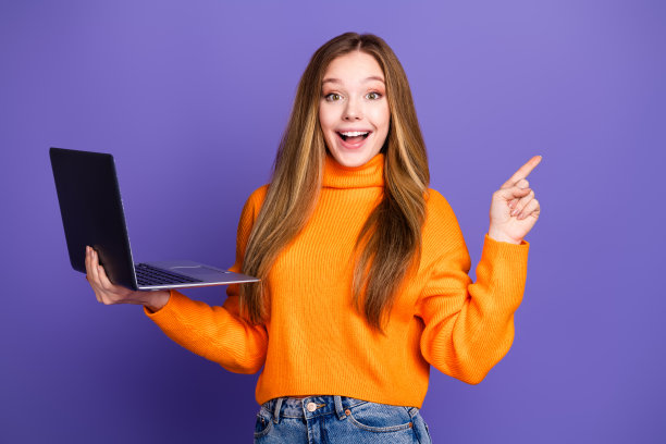青年肖像照片迷人的金发可爱的快乐的微笑女孩指导手指程序员课程与笔记本电脑孤立的紫罗兰色背景图片下载