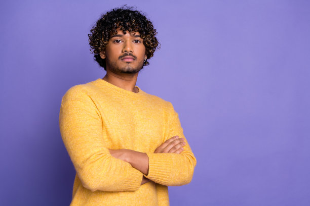 照片中自信有魅力的男人穿着时髦的黄色衣服，双臂交叉，在紫色的背景上孤立起来图片下载