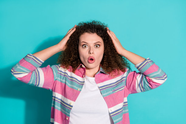 照片漂亮的年轻女子手臂触摸头发穿衬衫孤立的蓝绿色背景图片下载