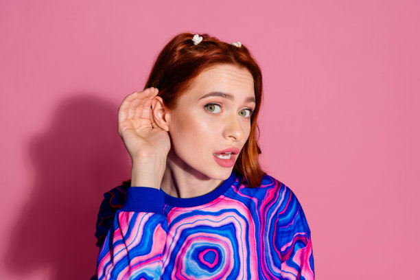 漂亮的年轻女孩的照片肖像听新闻秘密封面耳朵穿时髦的蓝色彩色服装孤立在粉红色的背景图片下载