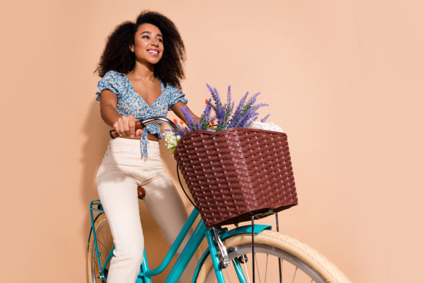 照片上光鲜迷人的女士穿着蓝色上衣骑自行车，空旷的空间孤立的米色背景图片下载