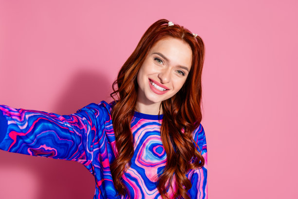 漂亮的年轻女孩的照片肖像，自拍照片穿着时髦的蓝色彩色服装，孤立在粉红色的背景下图片下载