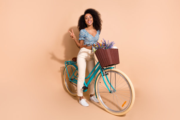 全身照片的闪亮迷人的女士穿着蓝色衬衫显示v字骑自行车空的空间孤立的米色背景图片下载