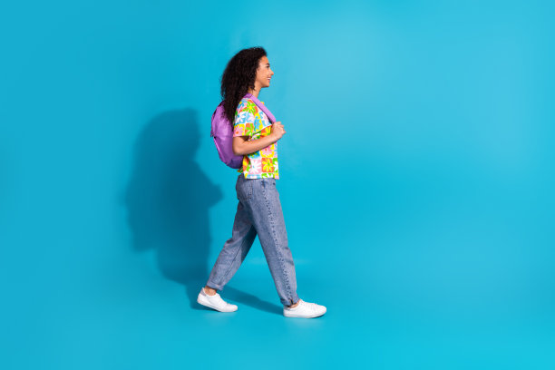 全身照片可爱迷人的女士穿着印花t恤背包走空空间孤立的蓝色背景图片下载