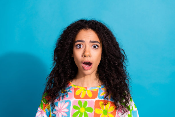 无语凝视的照片，女孩穿着时髦的印花衣服，在蓝色的背景上张开嘴图片下载