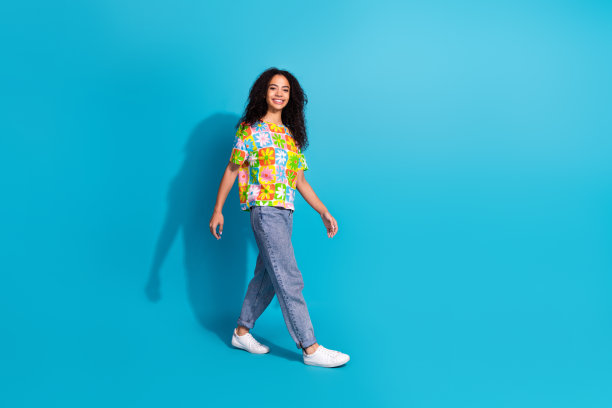全身照片闪亮迷人的女士穿着印花t恤走空空间孤立的蓝色背景图片下载