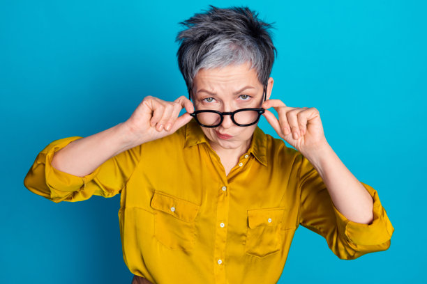 照片中古怪可疑的女人穿着衬衫，戴着眼镜，看着你孤立的蓝色背景图片下载