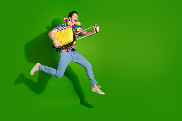 大喜的家伙穿着印花衬衫牛仔裤项链与旅行箱运行的全尺寸照片看起来空白空间孤立的绿色背景图片下载
