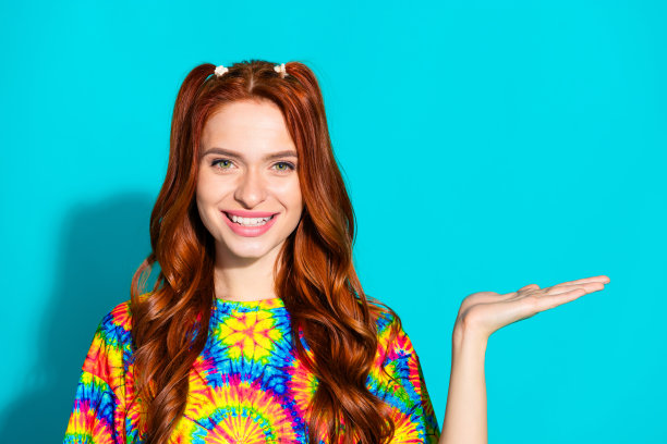 漂亮的年轻女孩的照片肖像持有空白空间穿着时髦的彩色服装孤立的海蓝宝石色背景图片下载