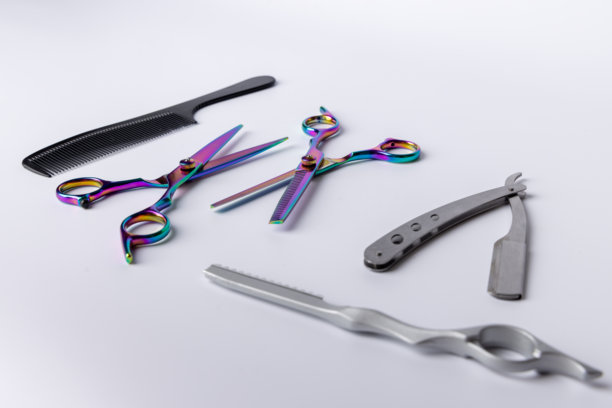 各种理发工具整齐地摆放在白色背景上的俯拍照片。剪刀、剪子、剃刀和梳子放在中间图片下载
