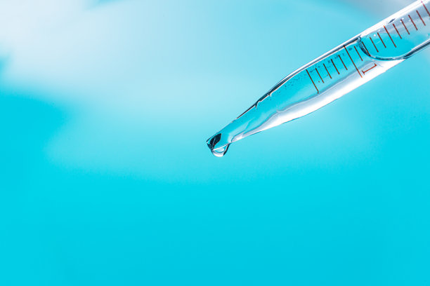 蓝色科学实验背景特写，蓝色背景中，不同大小气泡的凝胶从实验室滴管流出，进入培养皿图片下载