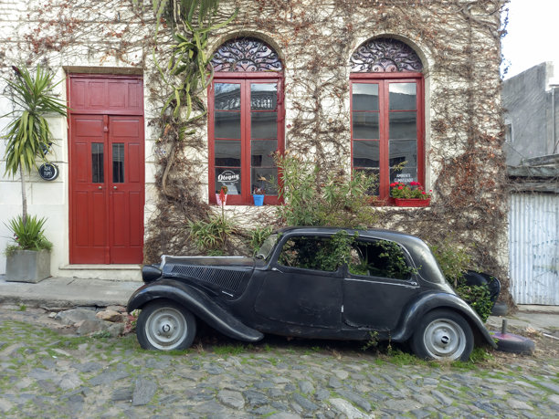 一辆1949年的雪铁龙牵引先锋车被遗弃在一条鹅卵石街道上，前面是一所爬满藤蔓的房子图片下载
