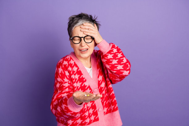 照片肖像漂亮的退休女性持有药丸治疗头痛穿时髦的红色服装孤立的紫色背景图片下载