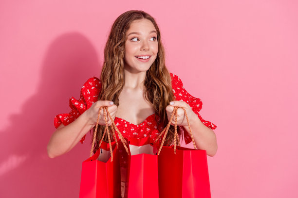 照片肖像迷人的十几岁的女人看起来空抱购物袋穿着时尚的红色衣服孤立在粉红色的背景图片下载