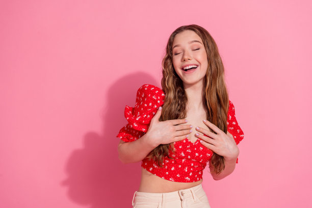 可爱的少女的照片肖像笑有乐趣穿着时尚的红色服装孤立在粉红色的背景图片下载