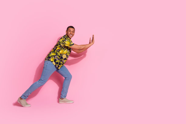 有魅力的年轻人的全身照片推墙空空间穿着时尚的热带印花衣服孤立在粉红色的背景图片下载